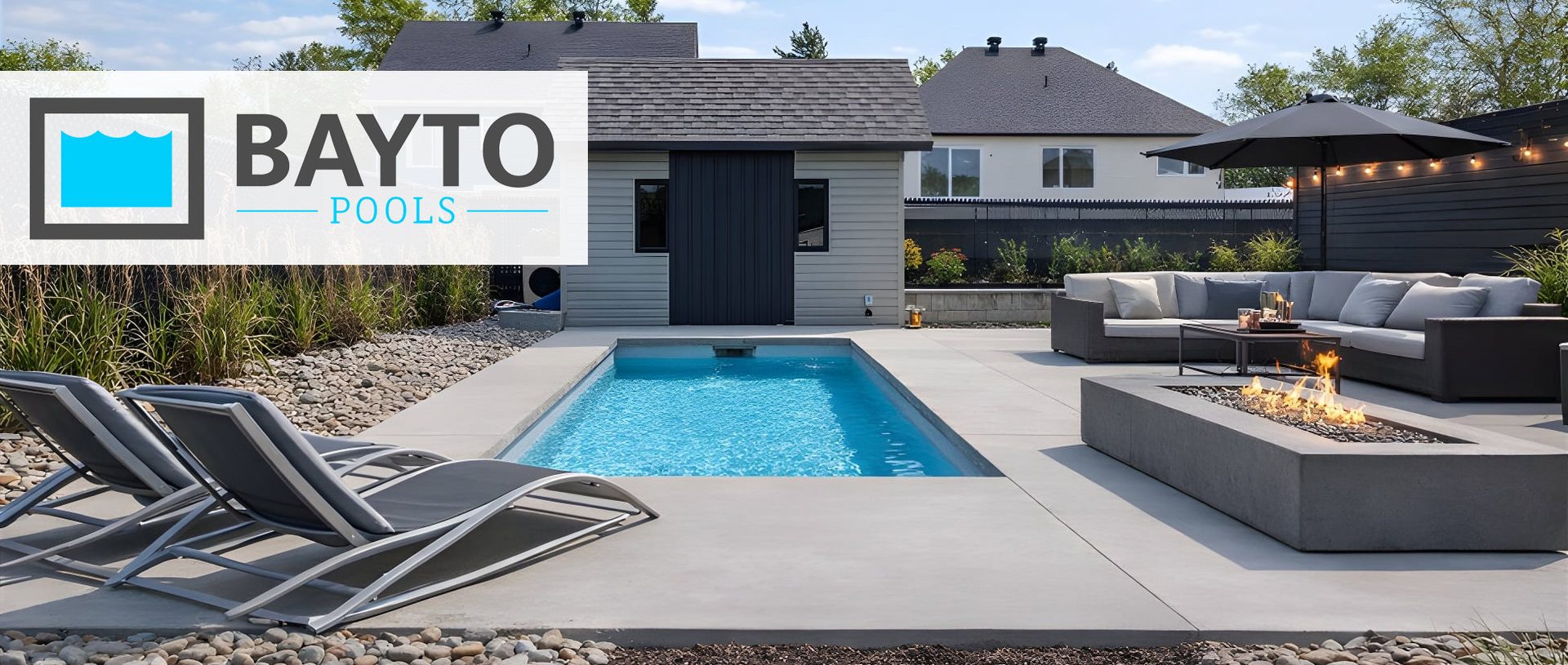 Bayto precast concrete pool on a concrete patio with lounge chairs and a fire table